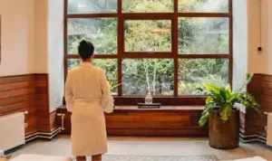 Persona en bata en el spa y sauna del Hotel Termas de Puyehue con vista a patio con vegetación