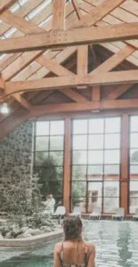 Mujer en piscina techada de Hotel Termas de Puyehue con piedra, madera y agua blackfriday